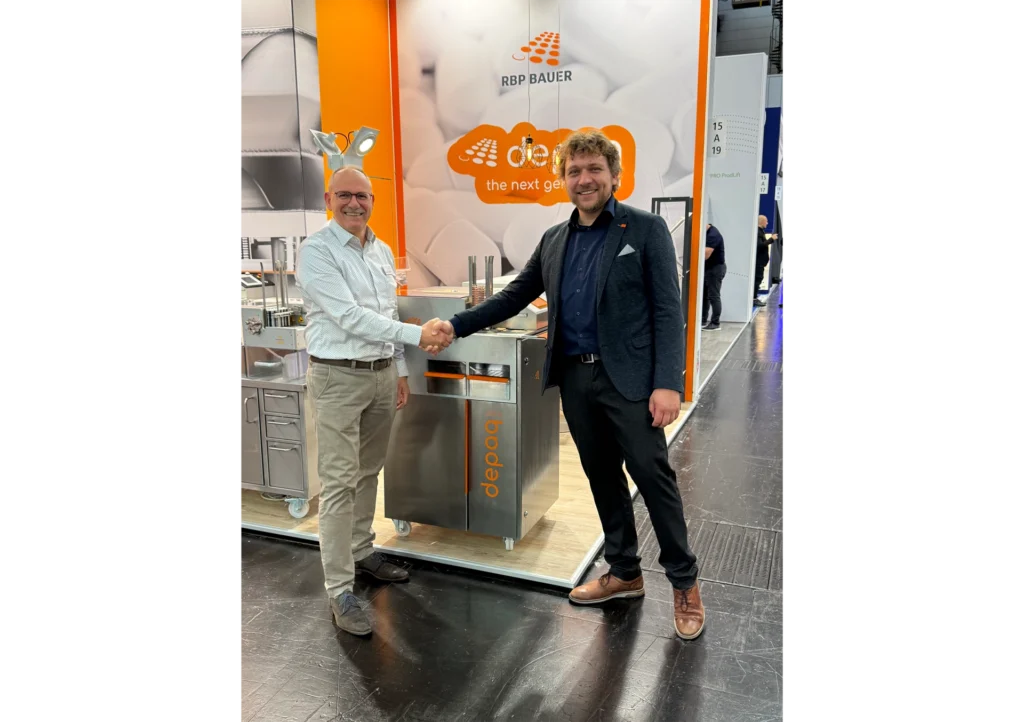 Henri Engel und Timo Heinen vor der depaq Blisterentleerungsmaschine auf der Interpack 2026
